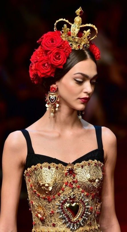 Modella con corona dorata, rose rosse fra i capelli e bustier in filigrana d’oro con cuore ex voto: Dolce & Gabbana, primavera-estate 2015.