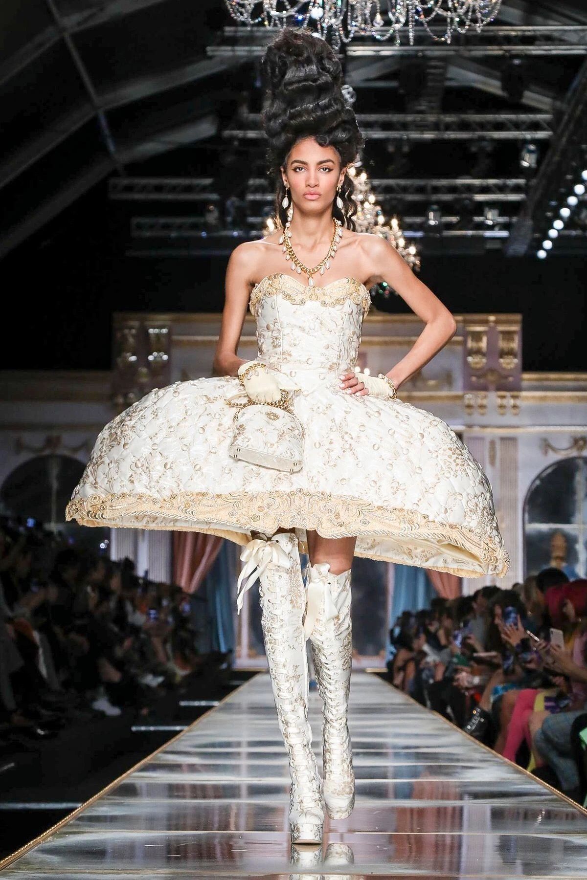 Abito corto avorio con gonna a paniere ricamata in oro e stivali alti allacciati, acconciatura alta incipriata: il rococò secondo Moschino, autunno-inverno 2020.
